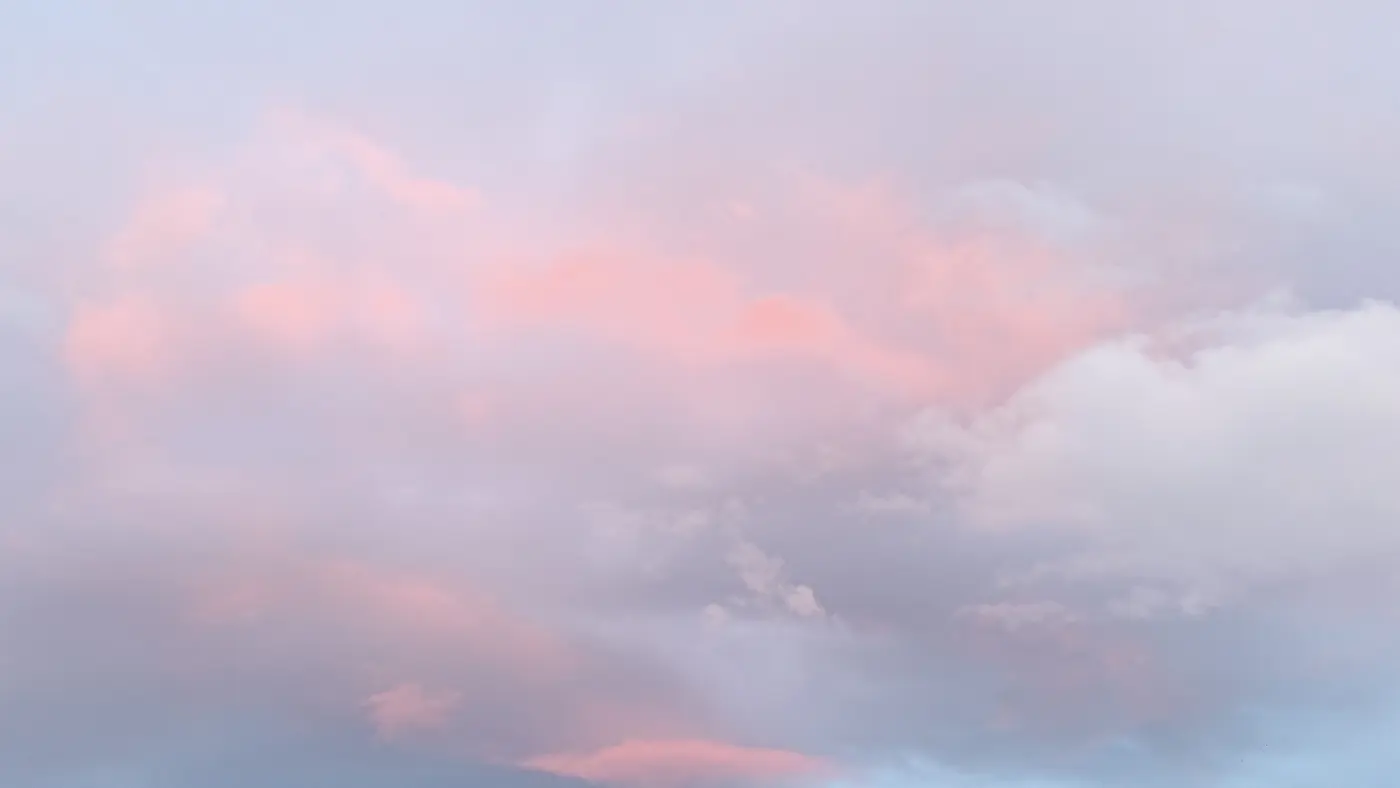 Un ciel de fin de journée sans aucun repère au sol : des nuages roses et gris étalés sur toute la largeur du cadre.