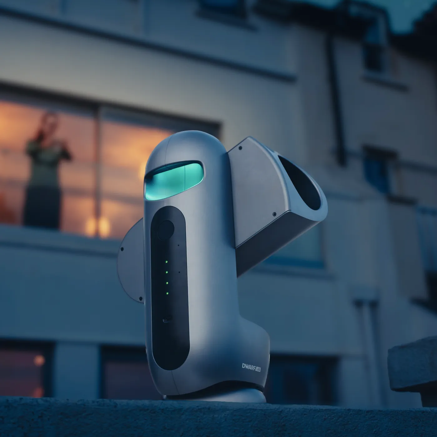 Le Draco sur une terrasse au crépuscule, bandeau lumineux allumé en cyan, devant la façade éclairée d'une maison où l'on devine une personne à la fenêtre.